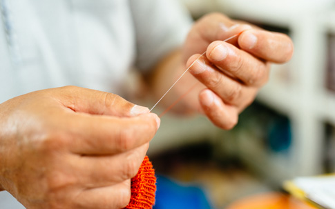 糸をほどきながら、靴下の構造を解説してくれる工場長の高垣和弘さん。この細い白い糸が裏糸になります。