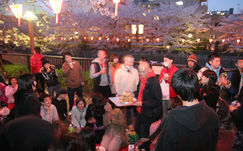 宮村さんが過去に開催したお花見の様子。中央の赤いマフラーが宮村さん。まさに大宴会！ 今年の開催を楽しみにしている人も多いそう。